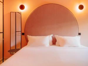 a bed with a large headboard and white pillows at Topazio Vibe Beach Hotel & Apartments - Adults Friendly in Albufeira +54 photos
