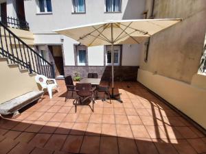 a patio with a table and chairs and an umbrella at Casa O Capitán in Corcubión