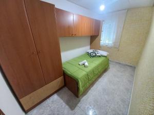 a small bedroom with a green bed and wooden cabinets at Casa O Capitán in Corcubión