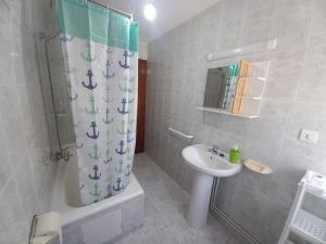 a bathroom with a sink and a shower curtain at Casa O Capitán in Corcubión