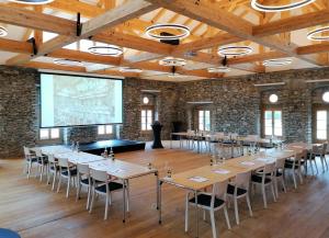 a large room with tables and chairs and a screen at Hochalmbahnen Chalets 1-03, Alpenrose, nahe Gondel, Hunde willkommen in Rauris