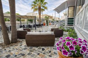a patio with tables and chairs and flowers at Hotiday Porto Cesareo in Porto Cesareo