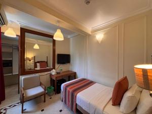 a bedroom with a bed and a desk and a chair at Hiltop Hotel in Mumbai