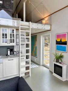 a loft bed in a kitchen with a living room at Steigen Cabin North in Steigen +32 photos