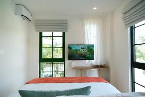 a bedroom with a bed and windows and a television at Sadec Garden Boutique Hotel in Ấp Tân Thành (2) +52 photos