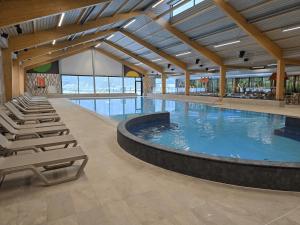 a large swimming pool with lounge chairs in a building at Vakantiepark Ommerland in Ommen