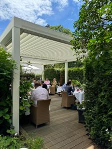 a group of people sitting at tables under a pergola at Gourmet Hotel Zur Post in Saint-Vith