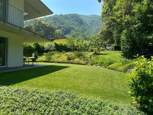 a yard with green grass and a garden with mountains at B&B Marysol in Arcegno