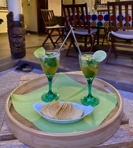 two glasses of margaritas and a plate of food on a table at Le Jardin du Saloum in Toubakouta