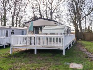 a white rv with a porch with a green umbrella at Sunflower Retreat, Caravan 61 in Morpeth