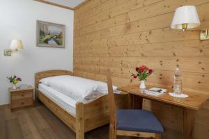 a bedroom with a bed and a wooden wall at Hotel Bad Serneus in Klosters +3 photos