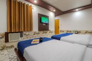 two beds in a room with a tv on the wall at Hotel Kanha in Haridwār +22 photos
