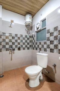a bathroom with a toilet and a window at Hotel Kanha in Haridwār