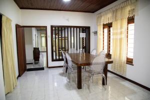 a dining room with a wooden table and chairs at Villa Hatange in Weligama
