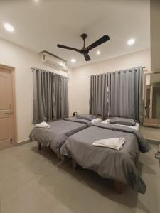 a bedroom with three beds and a ceiling fan at Comfort nest in Manipal in Manipal