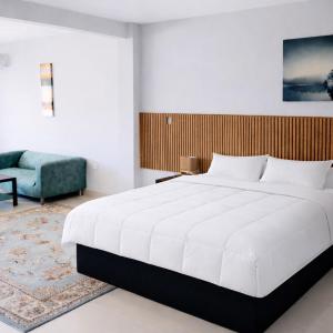 a bedroom with a large white bed and a blue couch at Tris Estates Hotel & Suites in Dwarzohn +53 photos