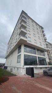 a tall white building with a car parked in front of it at Köşk Rezidans Apart in Aksaray