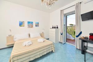 a white bedroom with a bed and a balcony at Don Giorgio Studios in Ischia Town