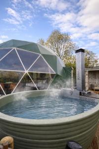 a hot tub with a green umbrella and water at Star Gazing Dome 3 with Log Burner & Optional Hot tub in Horspath