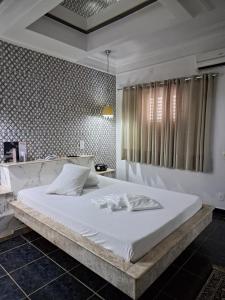 a bedroom with a large white bed with a window at Motel Marajas Mococa - Apartamento 03 in Mococa