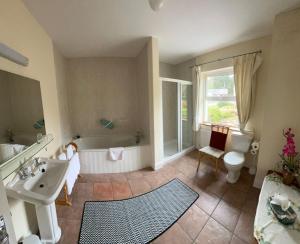 a bathroom with a tub and a sink and a toilet at Muxnaw Lodge in Kenmare +22 photos