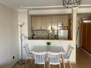 a kitchen with a table and white chairs and a kitchen at BERMUDAS-TURIS Apartamentos in Benidorm