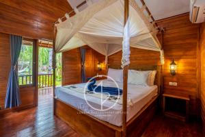 a bedroom with a canopy bed with wooden walls at Ings Garden Acommodation in Gili Islands