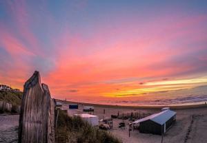a sunset at the beach with a building on the beach at Lovely Spacious Apartment in Zandvoort