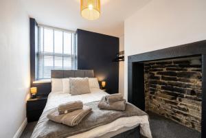 a bedroom with a large bed and a fireplace at Brontë Country 4 Bed Retreat with Fireplace in Oakworth