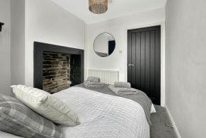 a white bedroom with a bed and a fireplace at Brontë Country 4 Bed Retreat with Fireplace in Oakworth +25 photos