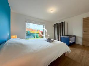a bedroom with a large white bed and a window at GC - La Voile Bleue in Wissant +49 photos