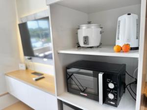 a kitchen with a black microwave on a shelf at Bears Nook - Marina Spatial Dumaguete in Piapi