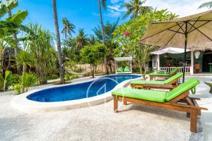 a pool with two green chairs and an umbrella at Ings Garden Acommodation in Gili Islands