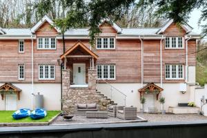 a large wooden house with two blue boats in front at Finest Retreats - Alpine Cottage in Symonds Yat