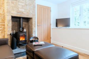 a living room with a leather couch and a wood stove at Finest Retreats - Alpine Cottage in Symonds Yat