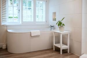 a white bathroom with a tub and a potted plant at Finest Retreats - Alpine Cottage in Symonds Yat +31 photos