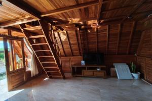 a living room with a wooden ceiling and a ladder at D'Cabin Villa Uluwatu in Uluwatu