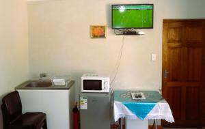 a room with a tv on the wall and a table with a microwave at Rosy Palm Sunrise in Upington
