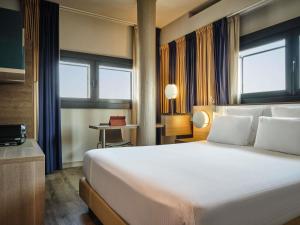 a hotel room with a large white bed and windows at Mercure Roma Centro Colosseo in Rome