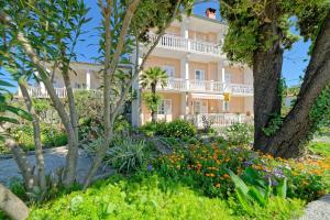 a large white building with trees and flowers at Rooms Milica in Palit