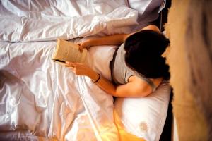 a person laying on a bed reading a book at Anima Resort Aghveran - Forest Retreat in Aghveran +21 photos