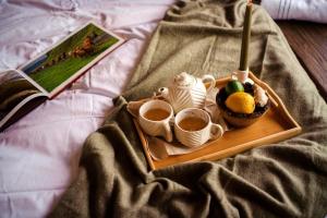 a tray with cups of coffee and a book on a bed at Anima Resort Aghveran - Forest Retreat in Aghveran