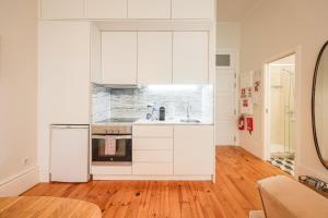 a kitchen with white cabinets and a refrigerator at Aliados Town Hall Central Apt by LuxiStay in Porto