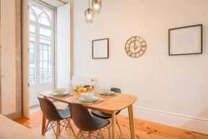 a dining room table with chairs and a clock on the wall at Aliados Town Hall Central Apt by LuxiStay in Porto +21 photos