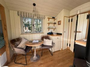 a small kitchen with a table and chairs in a tiny house at Chez Marguerite Luxury Shepherd's Hut and Sauna in Holt