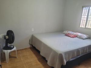 a bedroom with a bed and a fan and a chair at Casa Correntina BA 3 quartos in Correntina