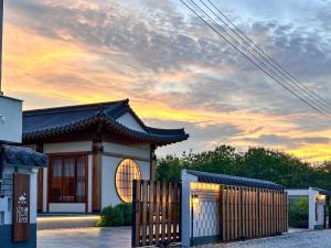 a building with a gate in front of a sunset at Krajokkaew Inyeon Khao Yai in Ban Khlong Yang