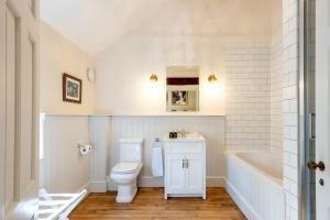 a bathroom with a toilet and a tub and a sink at The Coach House in Barlestone