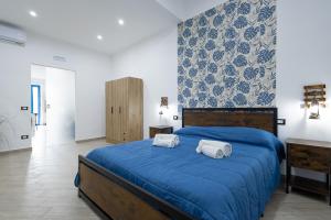 a bedroom with a blue bed with two towels at Scorcio di Mare By Dimora Hub in Balestrate