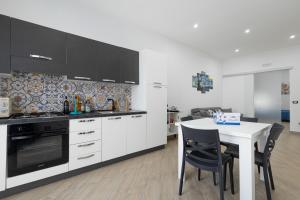 a kitchen with white cabinets and a table with chairs at Scorcio di Mare By Dimora Hub in Balestrate